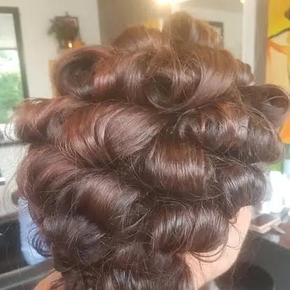 The back of a finished occasion updo, dark brown hair pinned into rows of soft curls