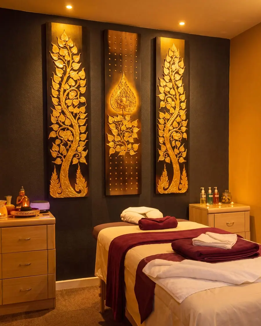 A Thai massage room seen from the corner, the couch running away at an angle beneath three carved gold wall panels